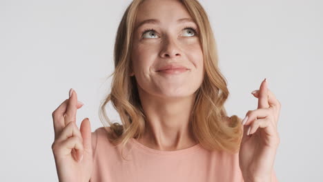 caucasian woman wistfully crossing fingers on camera.