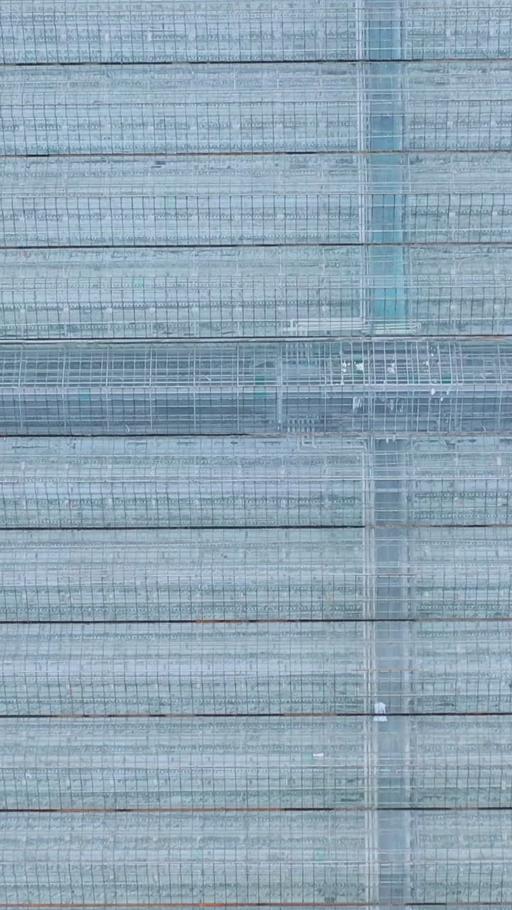 Aerial or flying over the greenhouses. Engineering structures near glass greenhouses. Vertical video