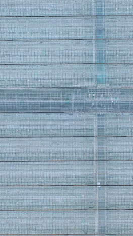 aerial or flying over the greenhouses. engineering structures near glass greenhouses. vertical video