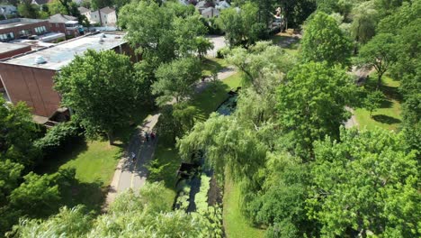 An-aerial-drone-view-over-a-park-in-Valley-Stream,-NY-with-a-stream-that-has-algae-on-it