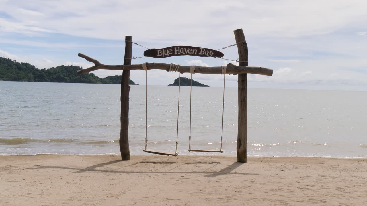 Popular Instagram landmark of a rustic wooden swing overlooking the ocean. Peaceful coastal scenery from Blue Haven Bay on Koh Chang in Thailand, ideal for travel, tourism and relaxation concepts