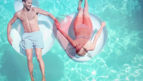 pareja acostada en flotador en la piscina