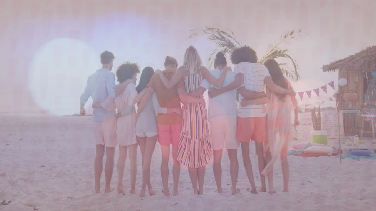 On beach, group of friends embracing near palm tree and hut, enjoying animation