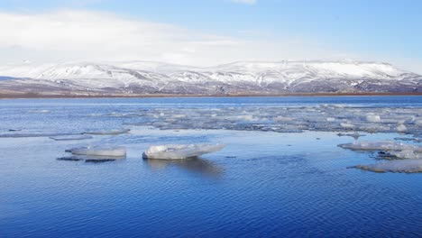 the cold, icy river of iceland by white mountains - wide shot