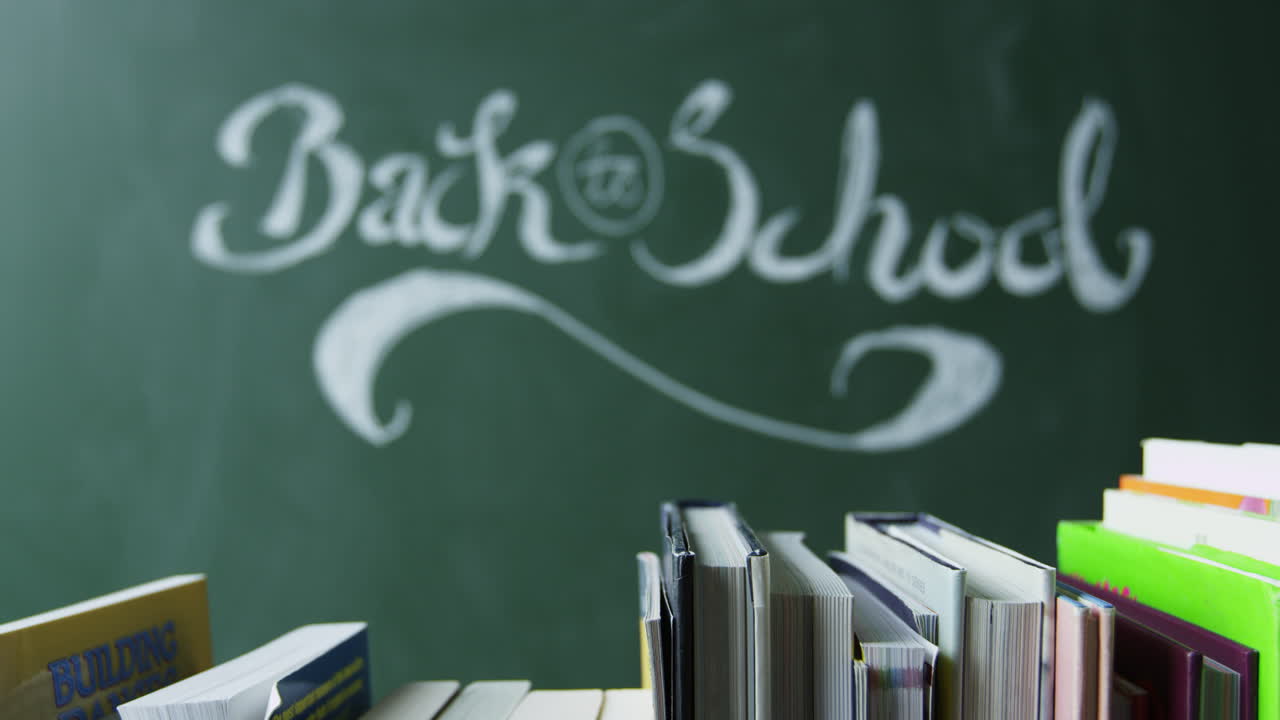 Zurück zur Schule handschriftlich an Tafel, Bücher im Vordergrund, auf R3D aufgenommen