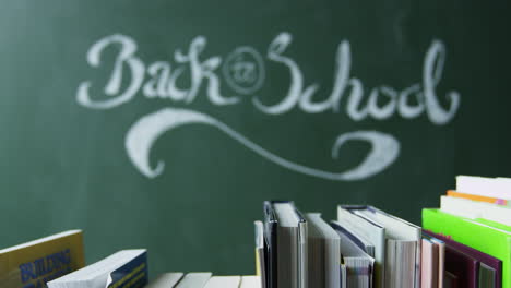 Back-to-school-handwritten-on-chalkboard,-books-in-foreground,-shot-on-R3D