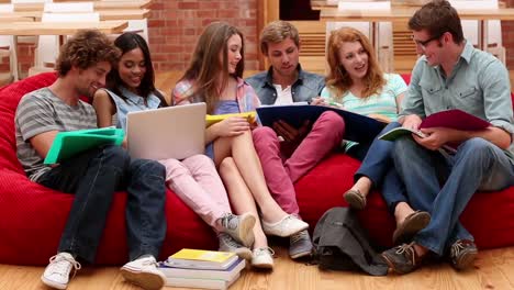 Happy-classmates-sitting-on-bean-bags-in-common-room