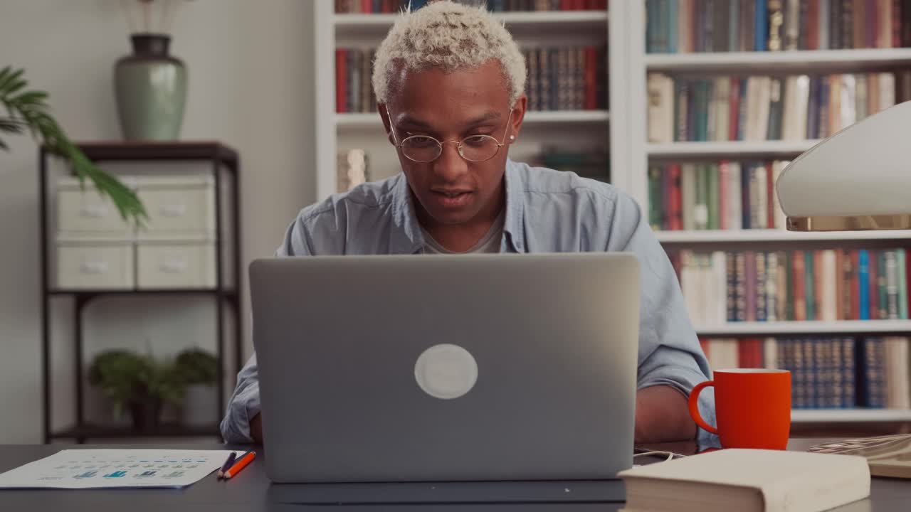 Confident african man using laptop sitting at his home desk