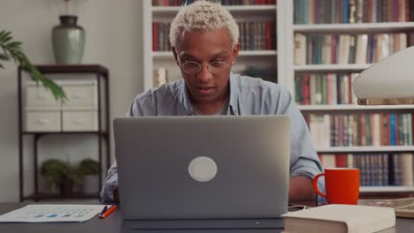 confident african man using laptop sitting at his home desk