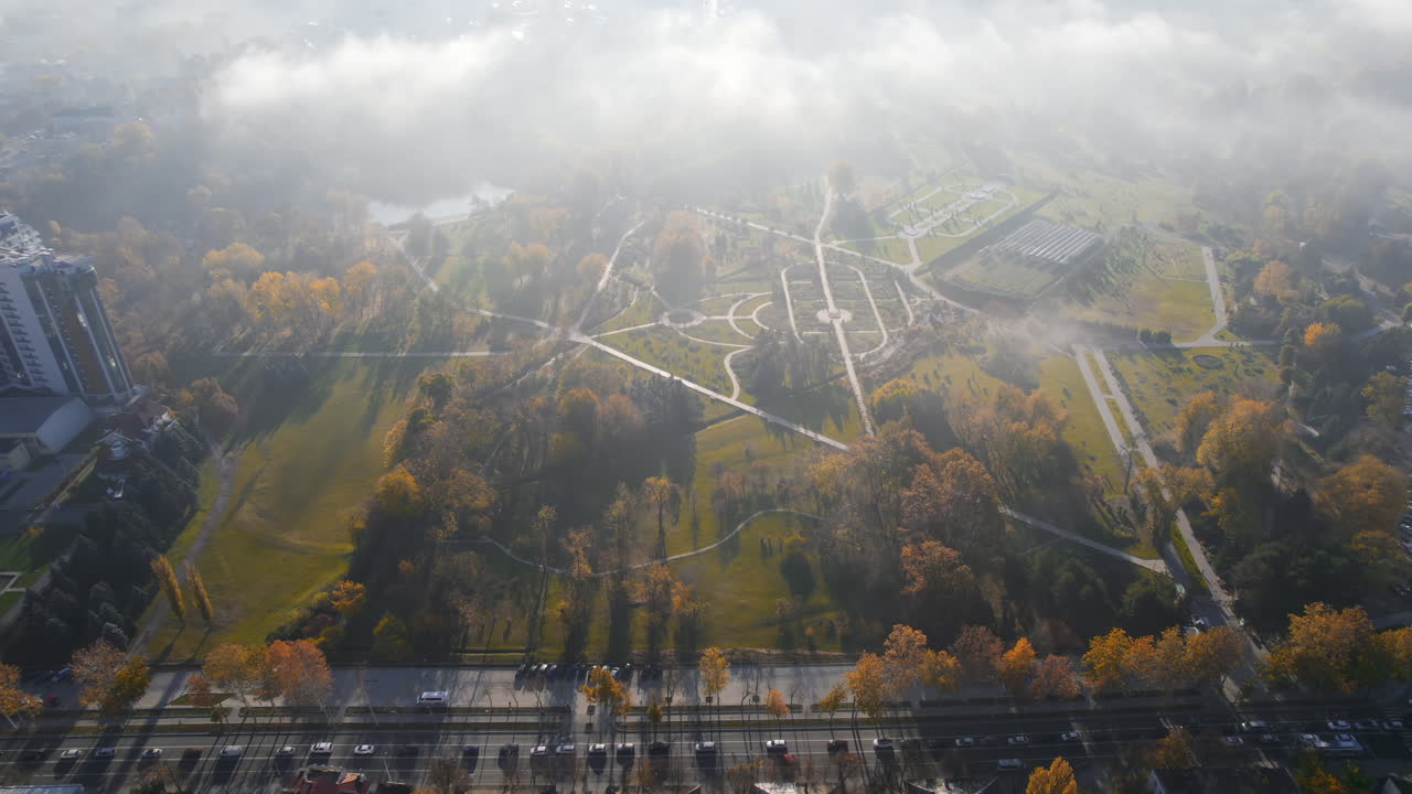 Aerial drone view of Chisinau at sunrise, Moldova. View of the city with fog in the air, modern residential buildings, Dendrarium park with yellowed trees