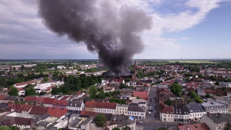 close aerial shot of black smoking burning building in kã¶then germany