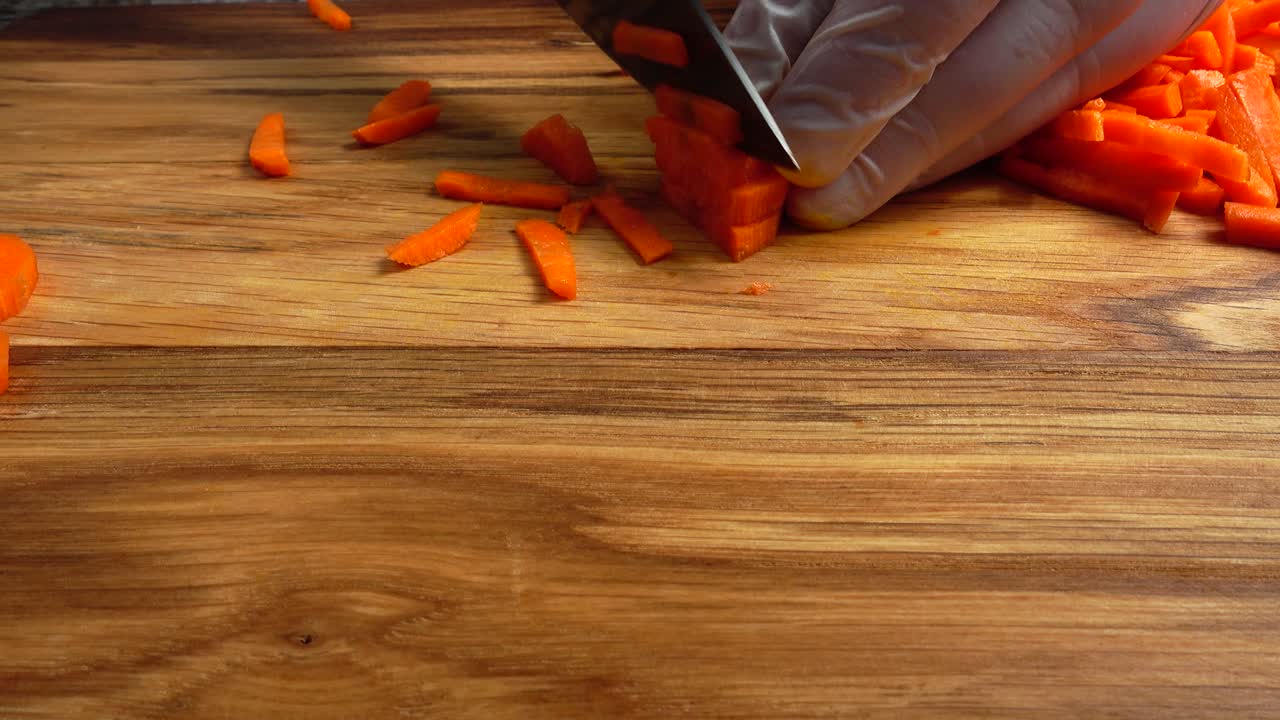 The cook cuts carrots on a cutting board