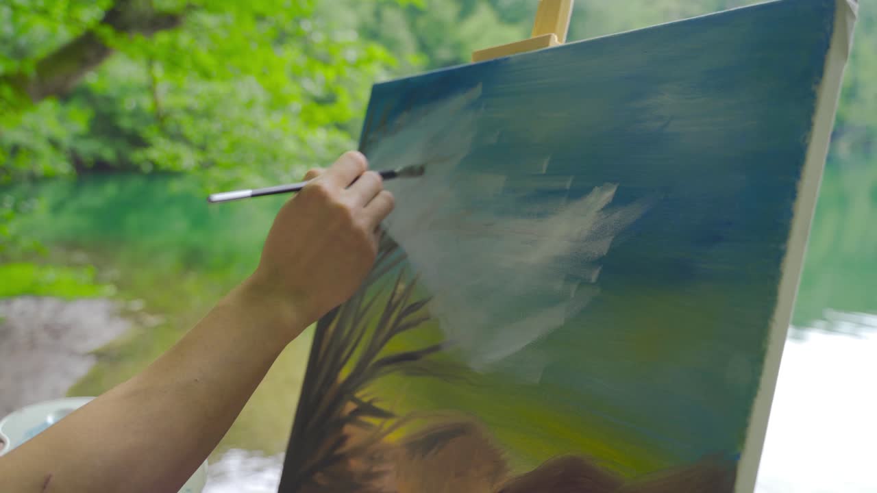pintor de primer plano pintando un cuadro junto al lago.