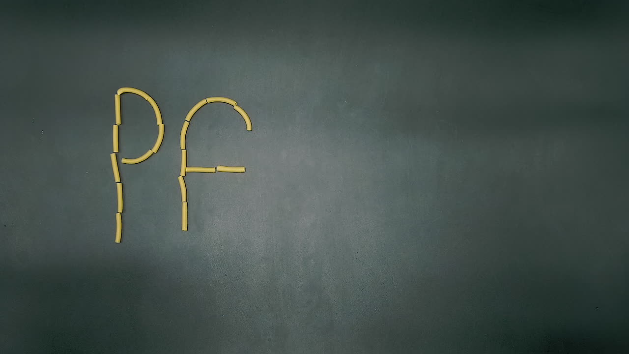 detener el movimiento de escribir la palabra pasta en un fondo de pizarra negra con pasta tipo macarrones