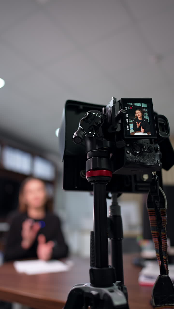 Filming a content for a modern blog using professional camera. Female blogger speaks confidently to camera. Low angle view. Blurred backdrop. Vertical video.