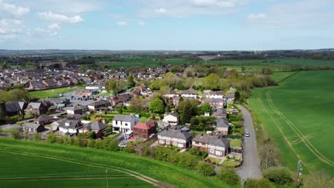 Aerial-view-rural-British-countryside-village-community-surrounded-by-farmland-fields,-Cheshire,-England