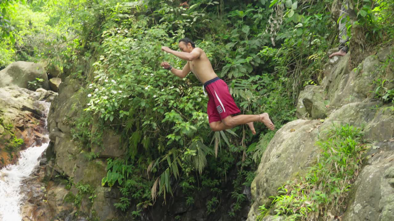 Person jumping into a refreshing waterfall pool