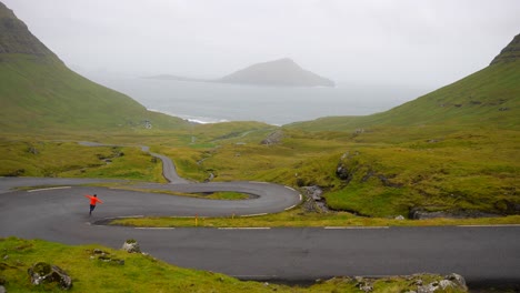 man running down nordradalsskard mountain pass with view of koltur island in faroe islands