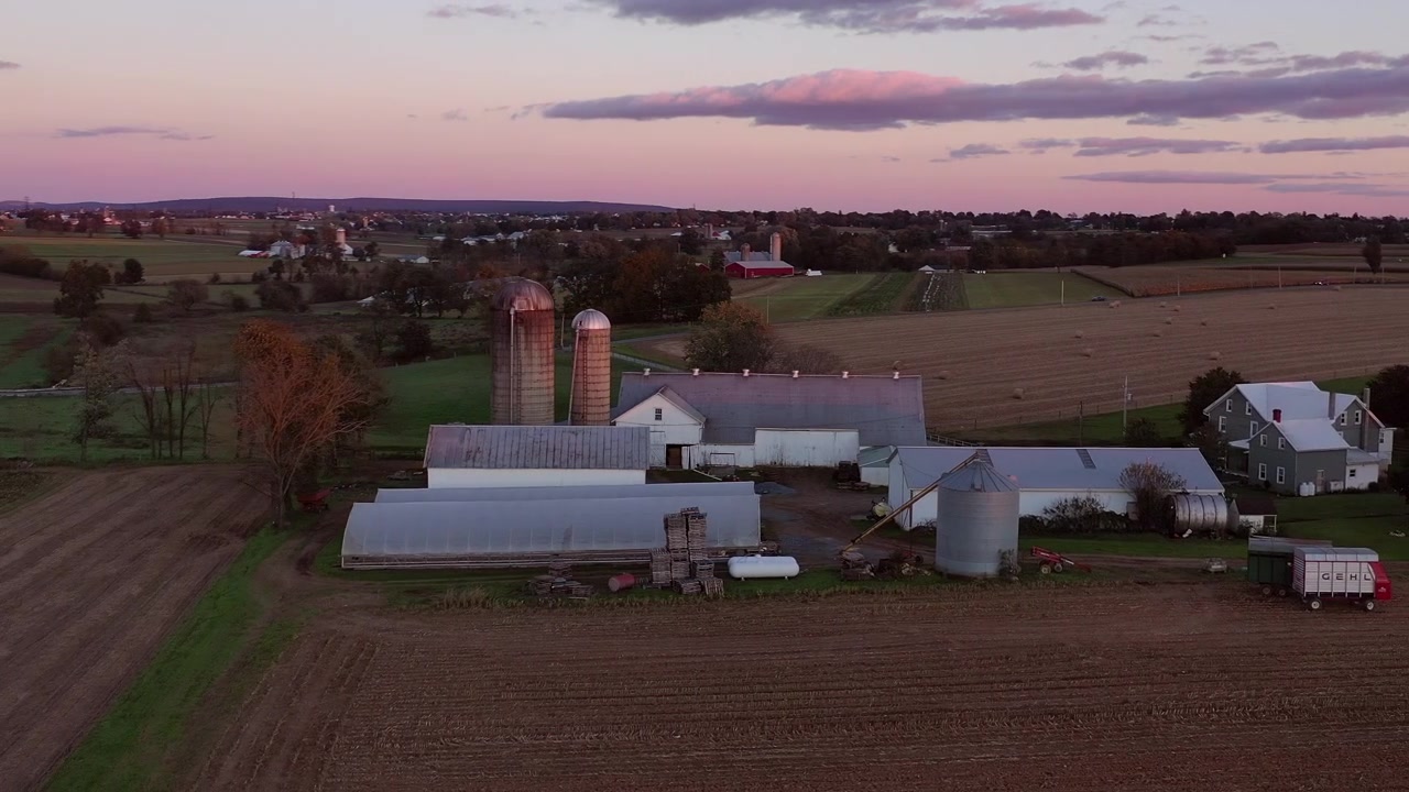 Incredible 360 drone shot of farmhouses and grain silos during a gorgeous autumn sunset