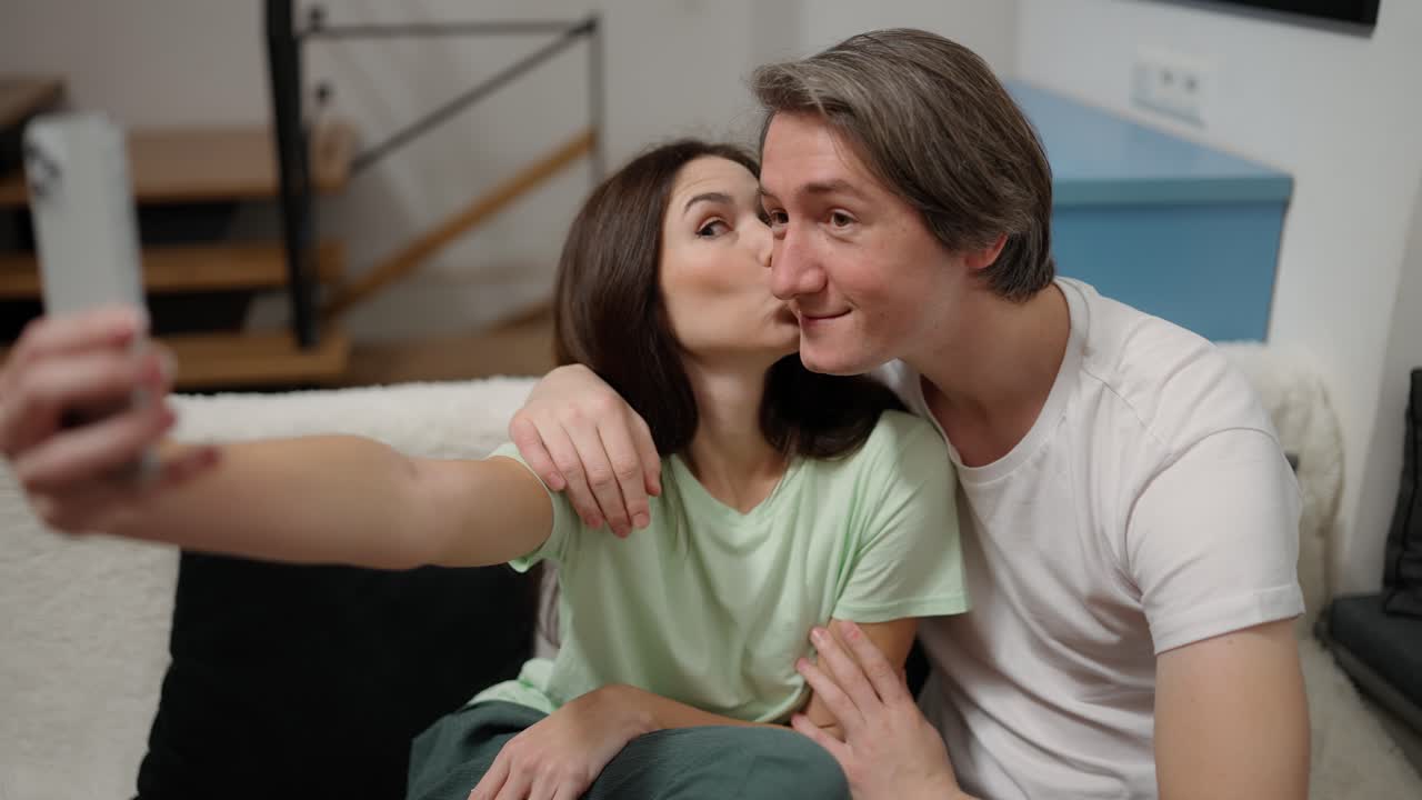 영감을 받은 사랑하는 남자와 여자가 개인 스마트폰으로 사진을 찍는 것을 받아들이고 있습니다.