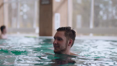 happy people are resting in thermal bath of modern wellness center man and woman are swimming together