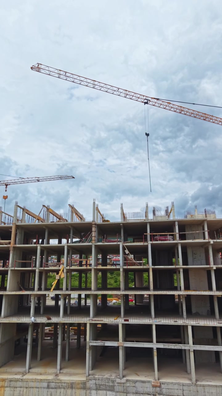 Construction activity on a multi-storey building with crane and cloudy sky in the background during daytime in an urban area