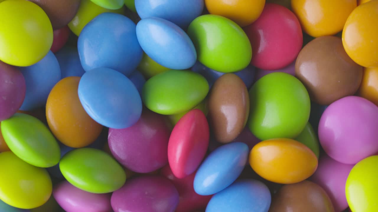 movimiento lento de primer plano de caramelos de chocolate redondos de colores, dragee. rotación y caída de caramellos de chocolate multicolores