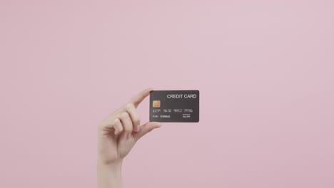 hand holding credit cards and showing on the pink background.