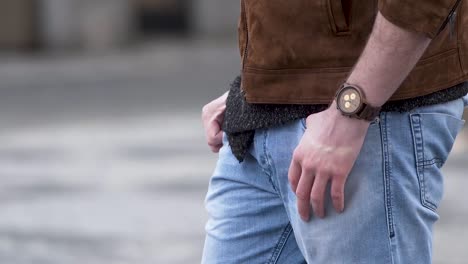 Stylish-man-wearing-a-watch-puts-hands-out-of-pockets,walks,closeup