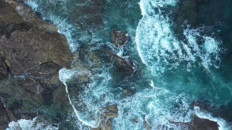 Veduta aerea dall'alto con drone di onde che si infrangono sulla costa rocciosa.