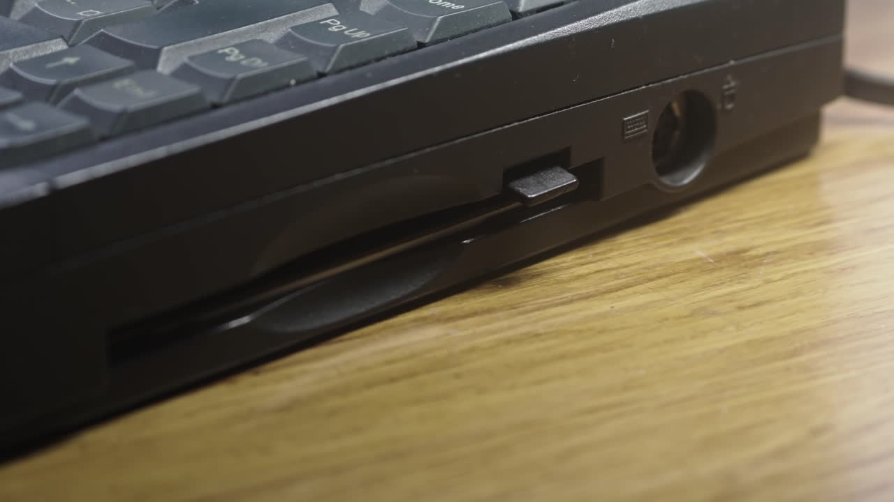 Computer user ejects floppy disc data storage from laptop CLOSE-UP