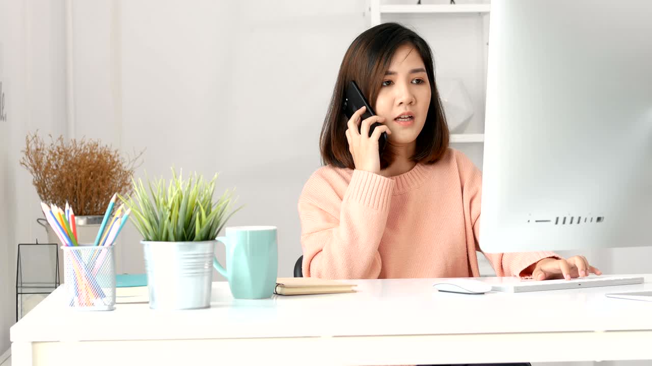 젊은 아시아 사업주들이 가정 사무실에서 컴퓨터 pc와 스마트 폰을 사용합니다.