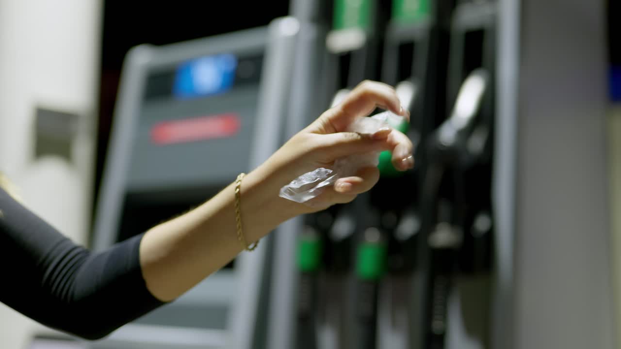 persona quitándose el guante desechable de seguridad después de repostar el coche en una gasolinera