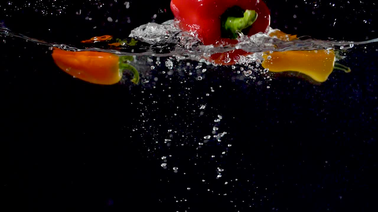 pimiento vibrante que se deja caer en el agua en cámara lenta