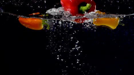 vibrant bell pepper being dropped into water in slow motion