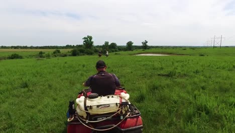 aerial following an atv following two cowboys on horses on the prairie of kansas