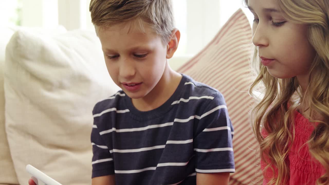 거실에서 디지털 태블릿을 사용하는 형제자매