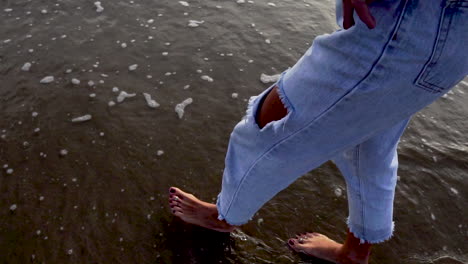 cerca de los pies caucásicos de una mujer caminando en la costa para bañarse