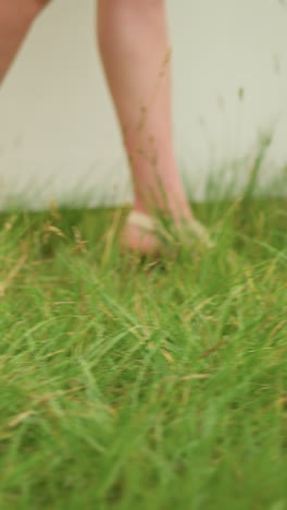 legs of two people walking through a green grass field. one is a man's leg wearing a black shoe, and the other is a woman's leg in sandals. focusing on the contrast between the footwear and the