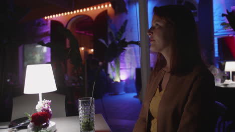 woman enjoying a cocktail at a romantic outdoor restaurant at night