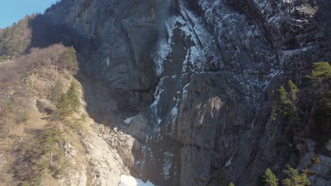 Vista-Aérea-De-Las-Rocas-Debajo-De-La-Cascada-De-Arpenaz-Que-Está-Rodeada-Por-Los-Altos-Picos-De-Los-Alpes-Franceses-Cerca-De-Montblanc