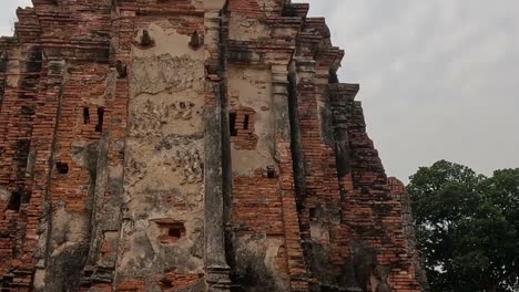 close-up view of an ancient brick structure with intricate details and a cloudy sky backdrop.