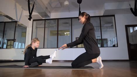 a female trainer and a girl gymnast in the hall during a rehearsal a female trainer and a girl gymnast in the hall during a rehearsal stretching before training