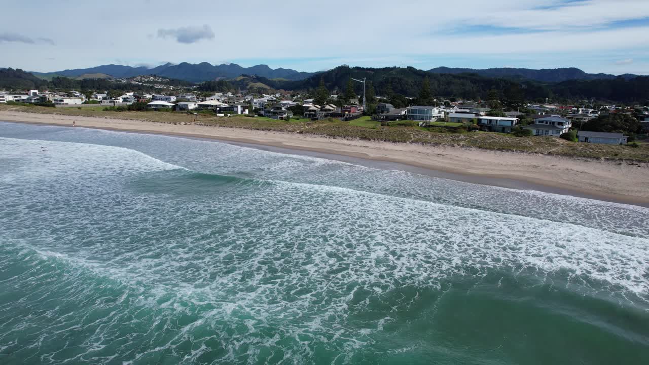 las olas espumosas del océano se estrellan en la playa de whangamata en coromandel, nueva zelanda.