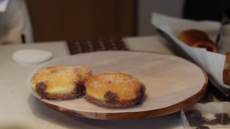 baker putting sweet berliners on tray in bakehouse