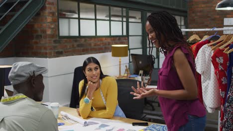 diseñadores de moda diversos felices usando las medidas de cinta discutiendo el trabajo en la oficina