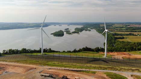 aerial static shot of wind turbines moving above susquehanna river on summer day, renewable energy theme