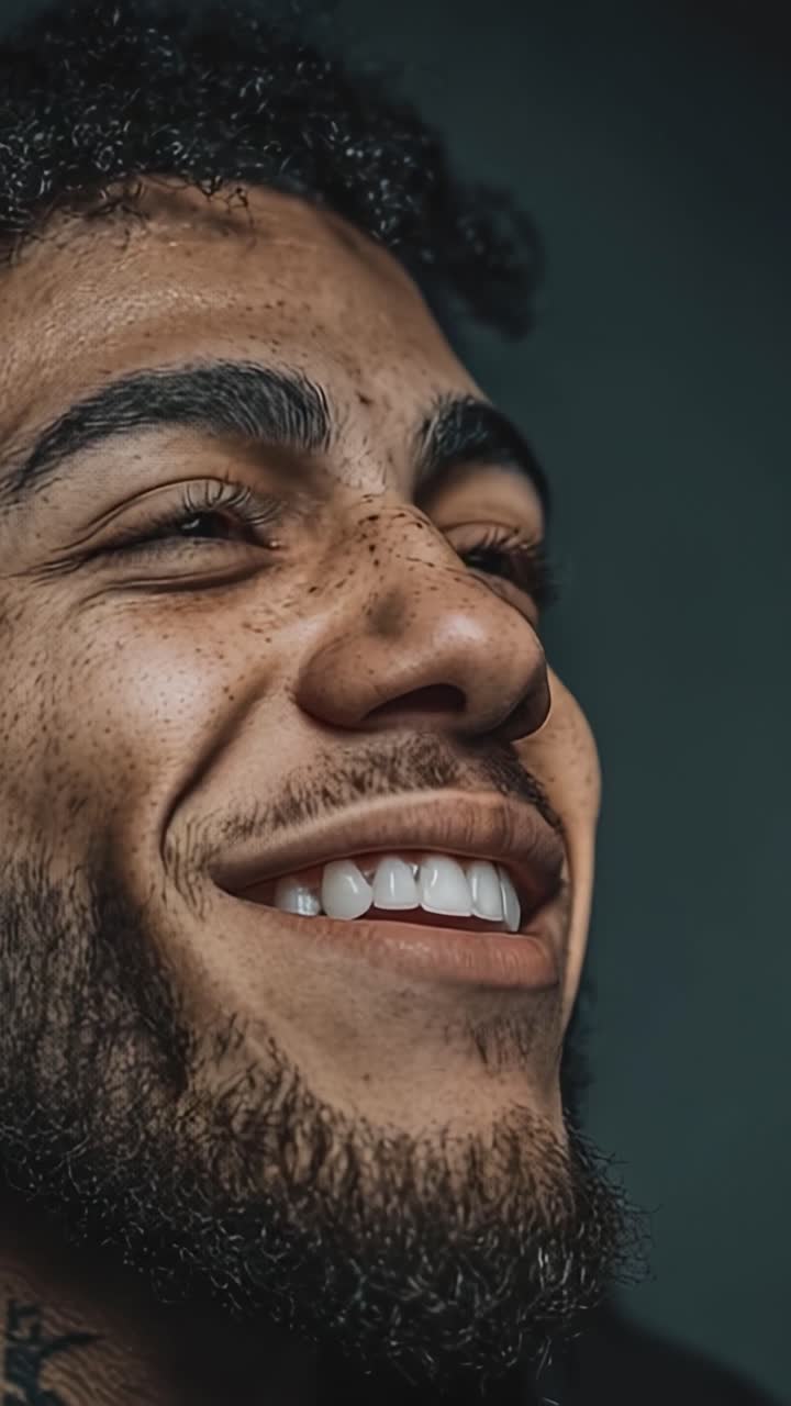 Ritratto espressivo di un giovane uomo sorridente con lentiggini e barba, che cattura gioia e felicità in un primo piano