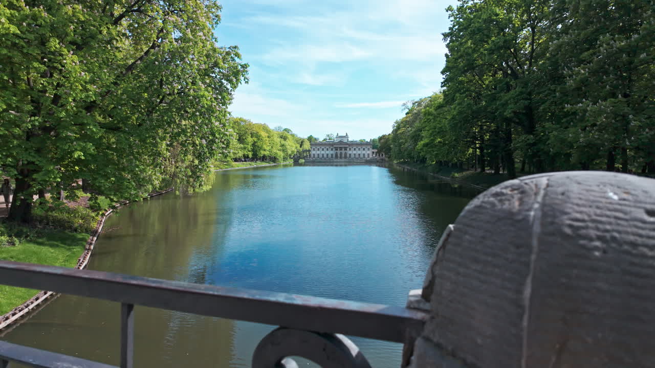 A scenic view of Pałac na Wyspie, Warsaw, with trees and water reflecting the sunlight