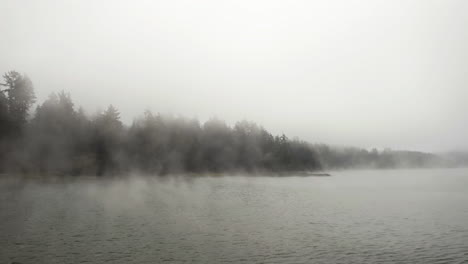 aerial tracking shot low over water surface on a misty lake, cloudy day in usa